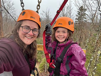 Teacher with a female students smiling and wearing safety hats outside