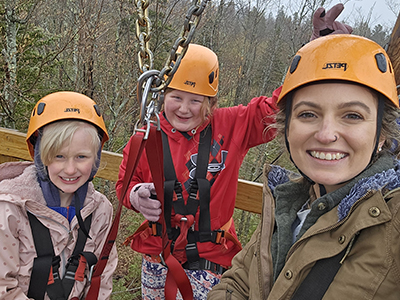 Teacher with two students smiling and wearing safety hats outside