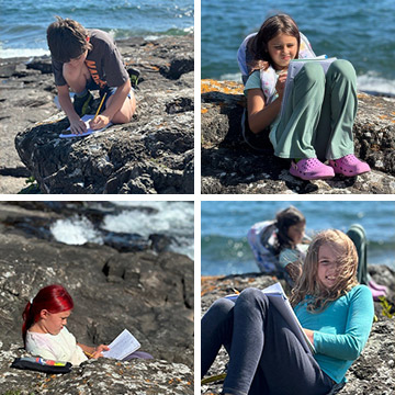 Students doing schoolwork on the rocks by the beach