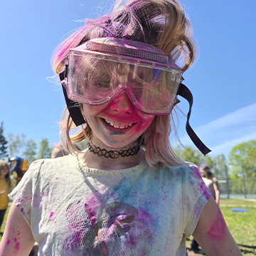 A student wearing goggles covered in chalk